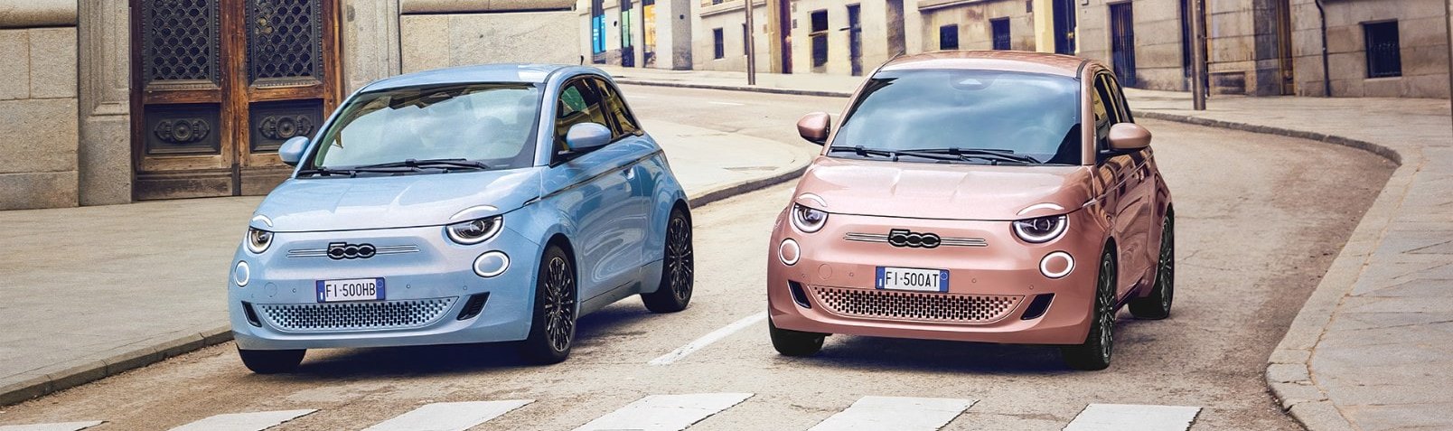 Fiat 500e in blue and pink next to each other on a road